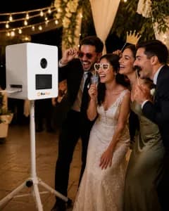 Hochzeitsgäste lachen mit Requisiten vor der BoxShot Fotobox